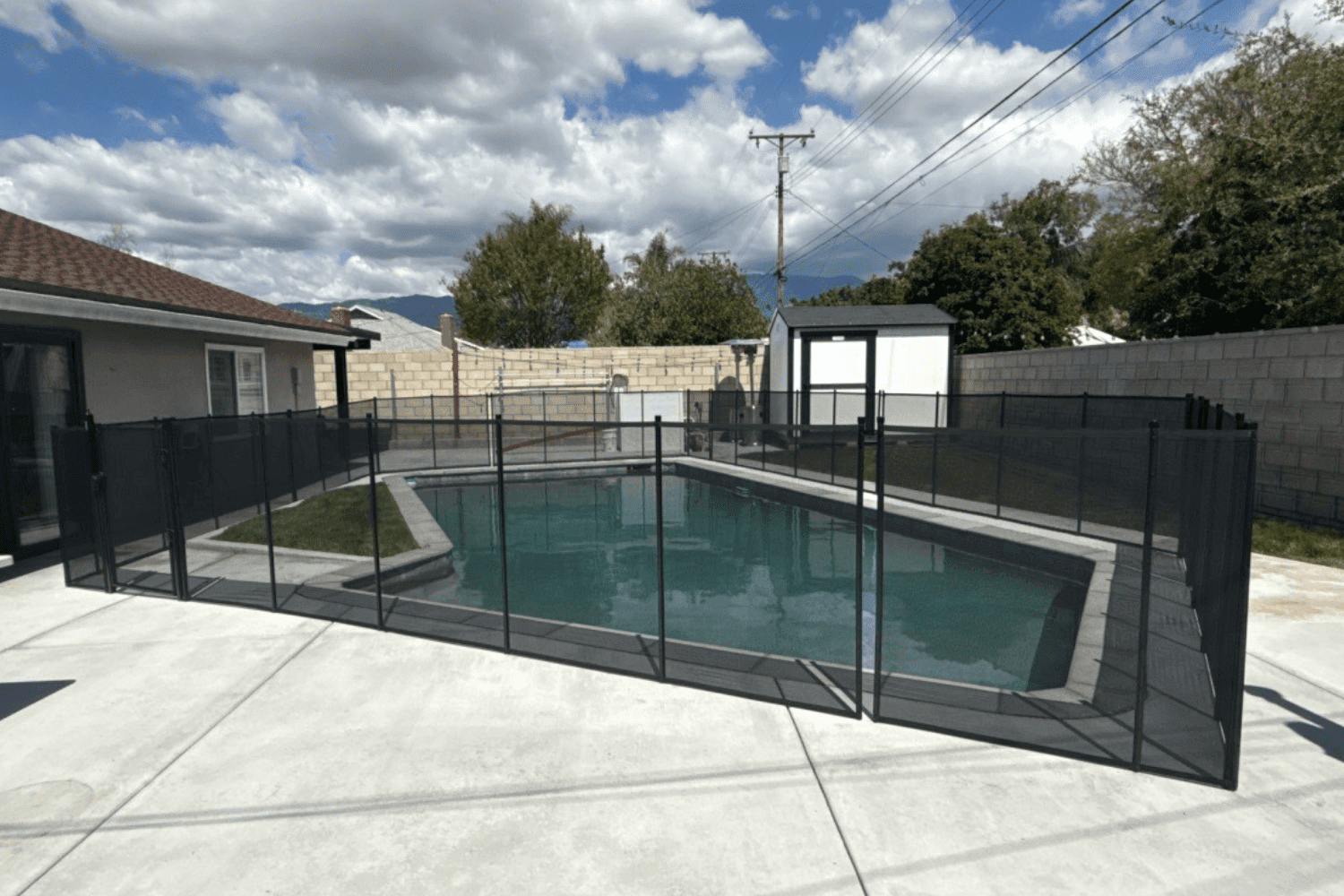 10 questions pool fence Backyard swimming pool with a black mesh removable pool fence installed surrounding it